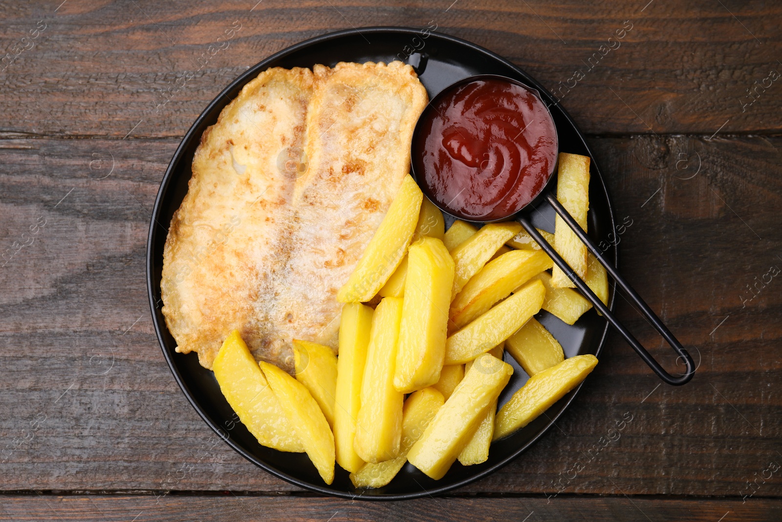 Photo of Delicious fish and chips with ketchup on wooden table, top view