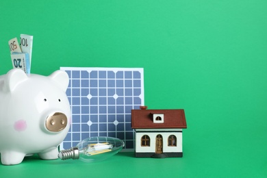 Photo of Composition with solar panel and piggy bank on white background