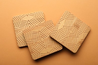 Photo of Stylish wooden cup coasters on orange background, flat lay