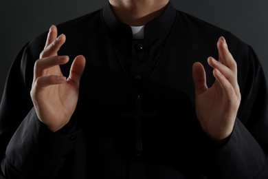 Photo of Priest with cross on black background, closeup