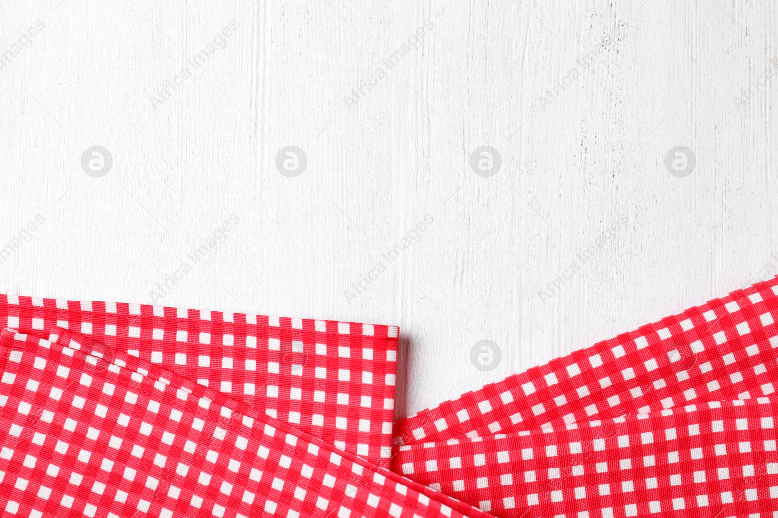 Photo of Checkered picnic napkins on wooden background, top view. Space for text