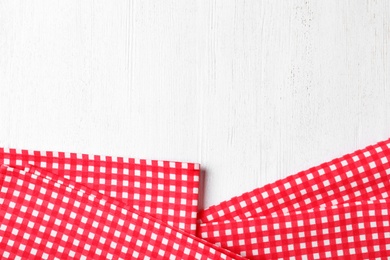 Photo of Checkered picnic napkins on wooden background, top view. Space for text