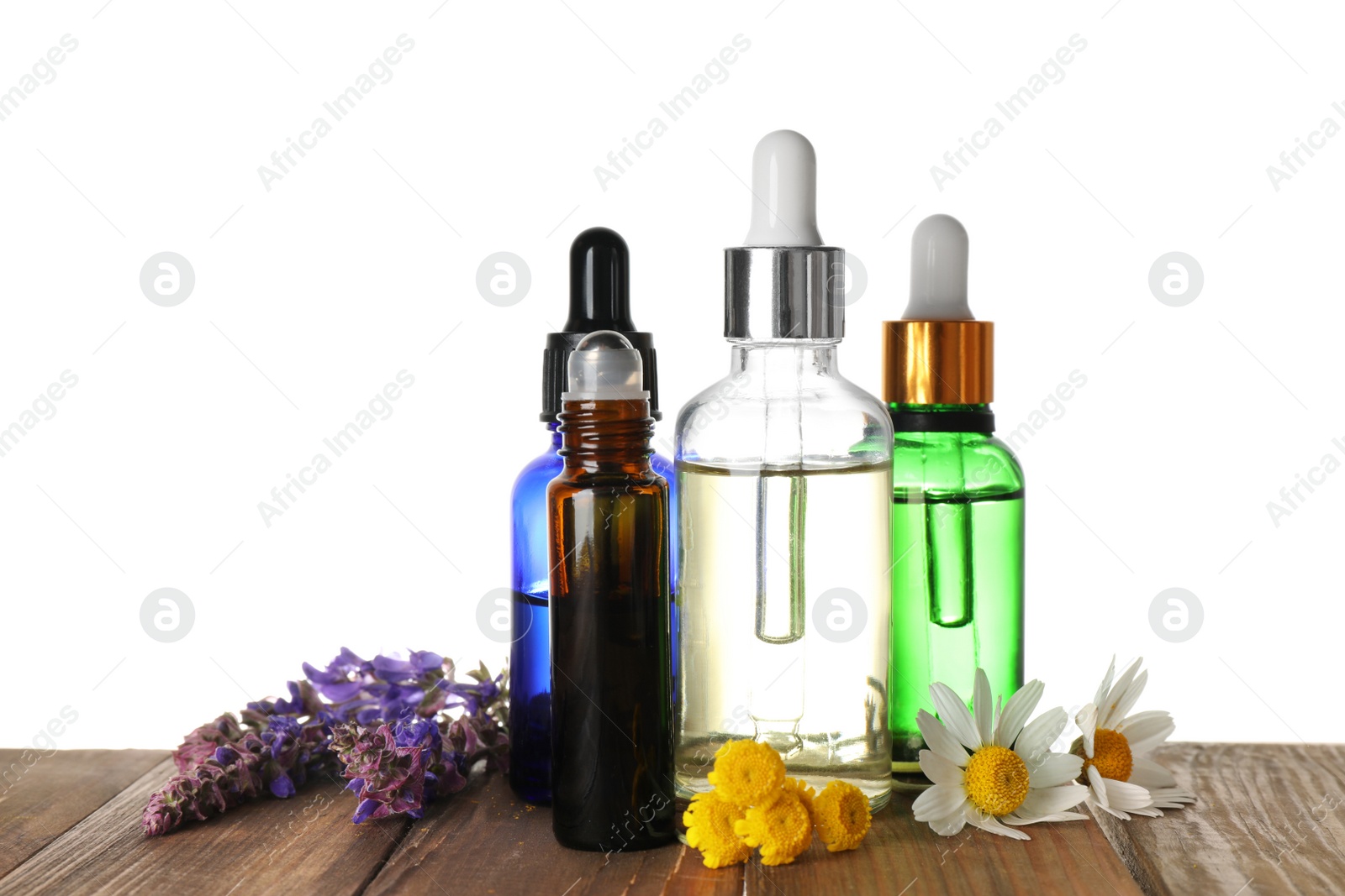 Photo of Bottles of herbal essential oils and wildflowers on wooden table, white background