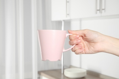 Photo of Woman holding pink cup at home, closeup