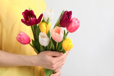 Photo of Girl holding bouquet of beautiful spring tulips on light background, closeup. International Women's Day