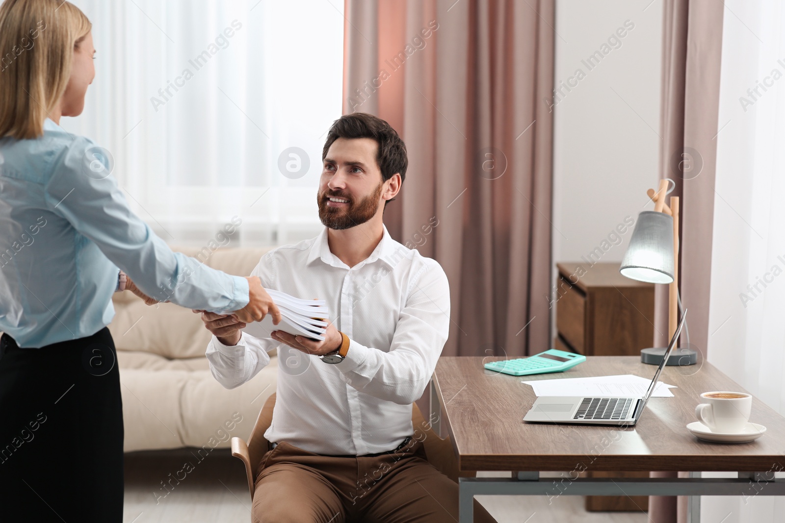 Photo of Woman giving documents to colleague in office