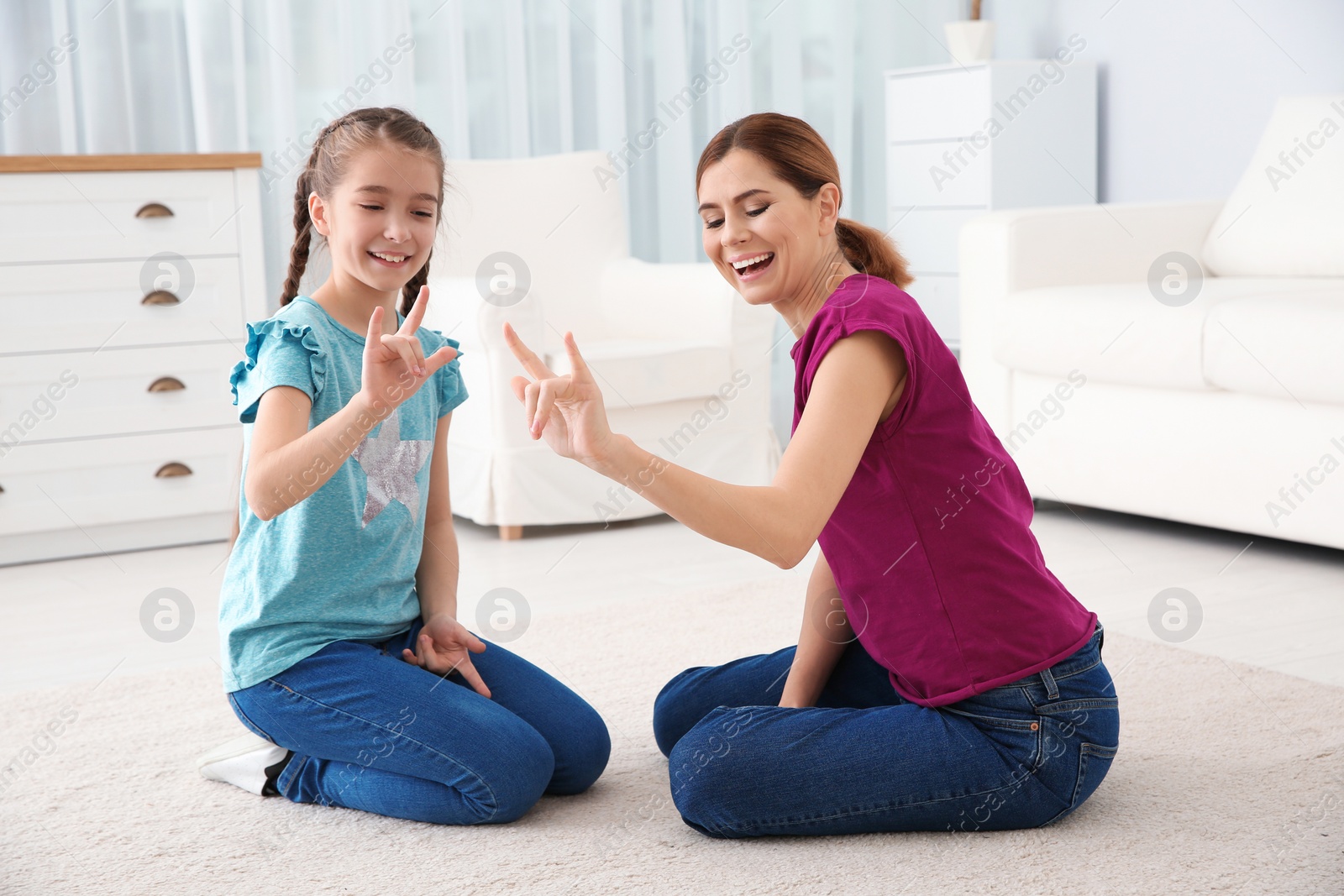 Photo of Hearing impaired mother and her child talking with help of sign language indoors