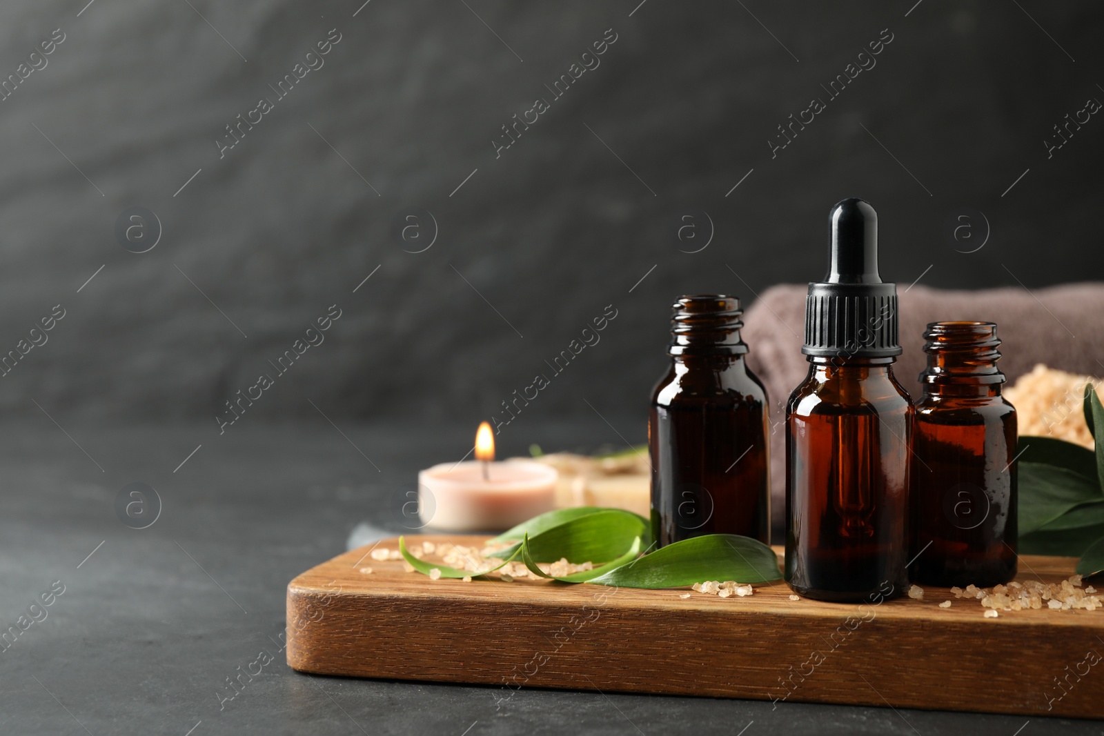 Photo of Composition with aroma oil bottles on grey table, space for text