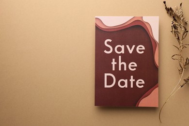 Photo of Beautiful card with Save the Date phrase and dry branch on beige background, top view. Space for text