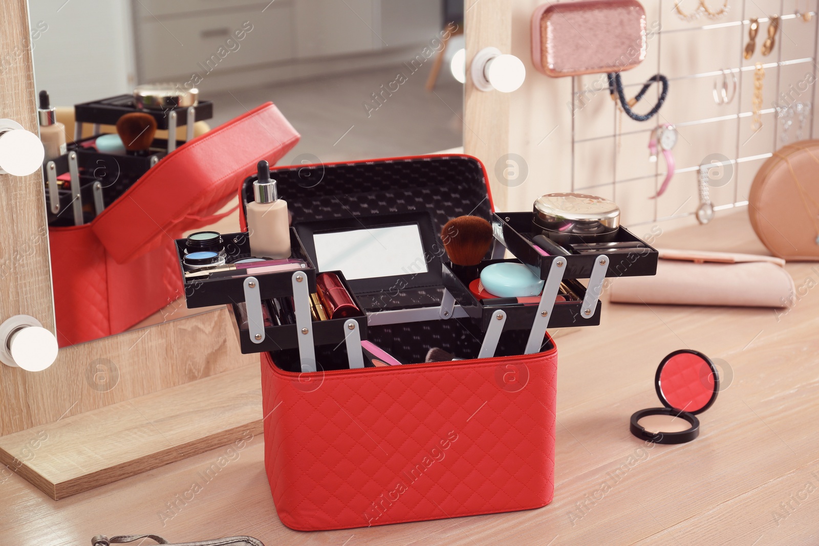 Photo of Beautician case with professional makeup products and tools on wooden dressing table