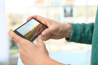Image of Man watching video on mobile phone at home, closeup