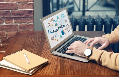 Image of Man using laptop with word FINTECH in office, closeup