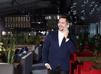 Young business owner talking on phone in his cafe
