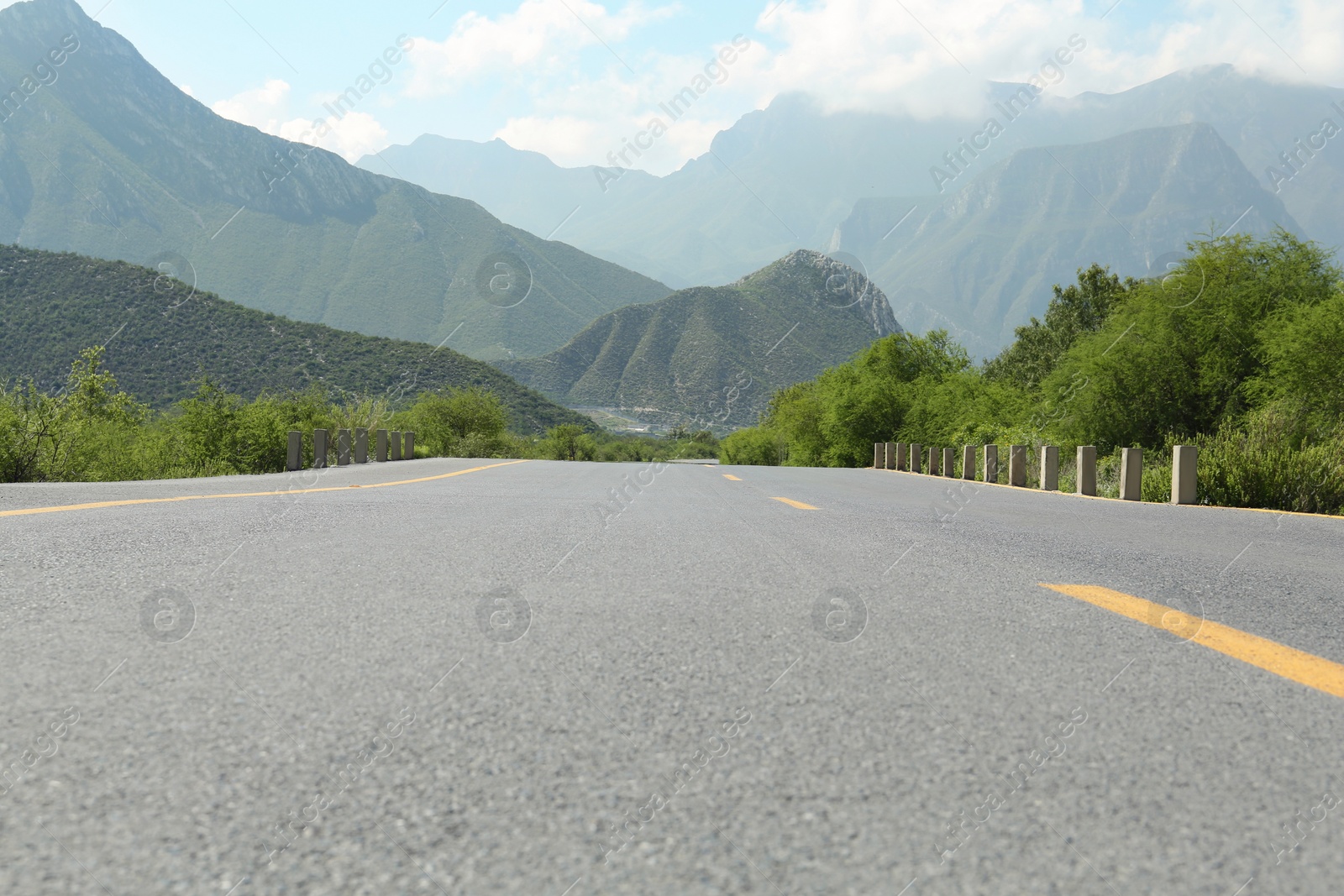 Photo of Picturesque view of big mountains and bushes near road under cloudy sky