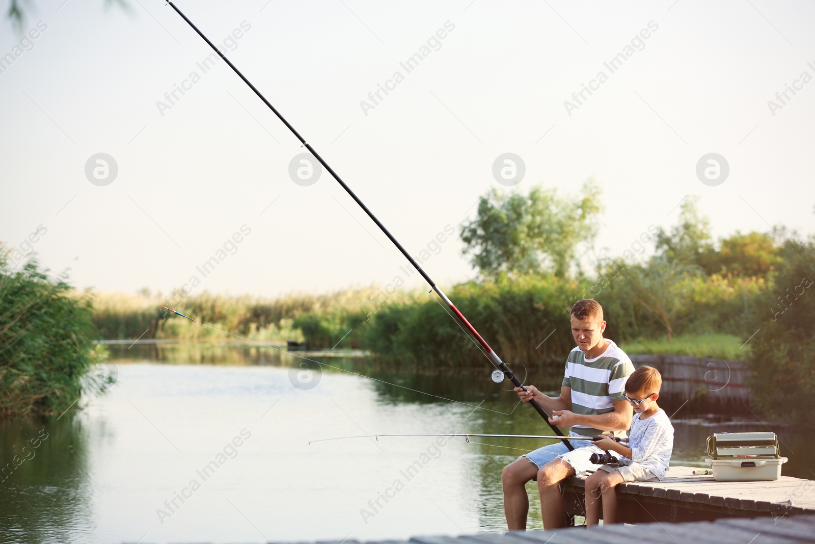 Photo of Dad and son fishing together on sunny day