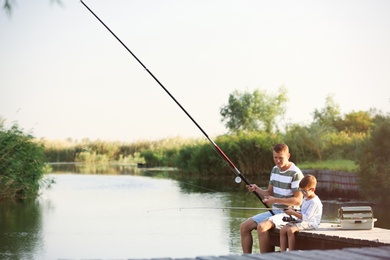 Dad and son fishing together on sunny day