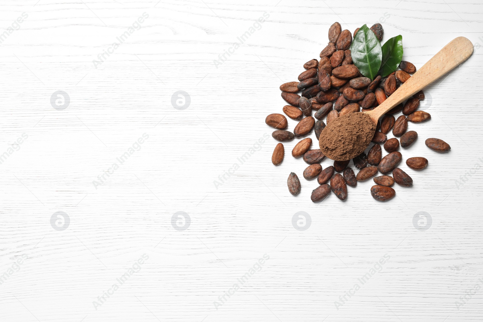 Photo of Flat lay composition with cocoa beans and powder on white wooden table, space for text