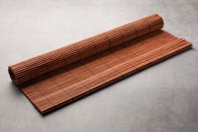 Photo of Rolled bamboo mat on grey table, closeup