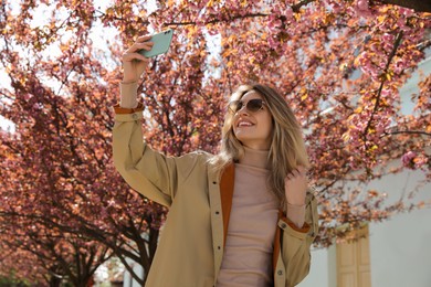 Photo of Young woman taking selfie on city street