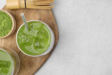 Delicious iced green matcha tea, powder and bamboo whisk on white table, top view. Space for text