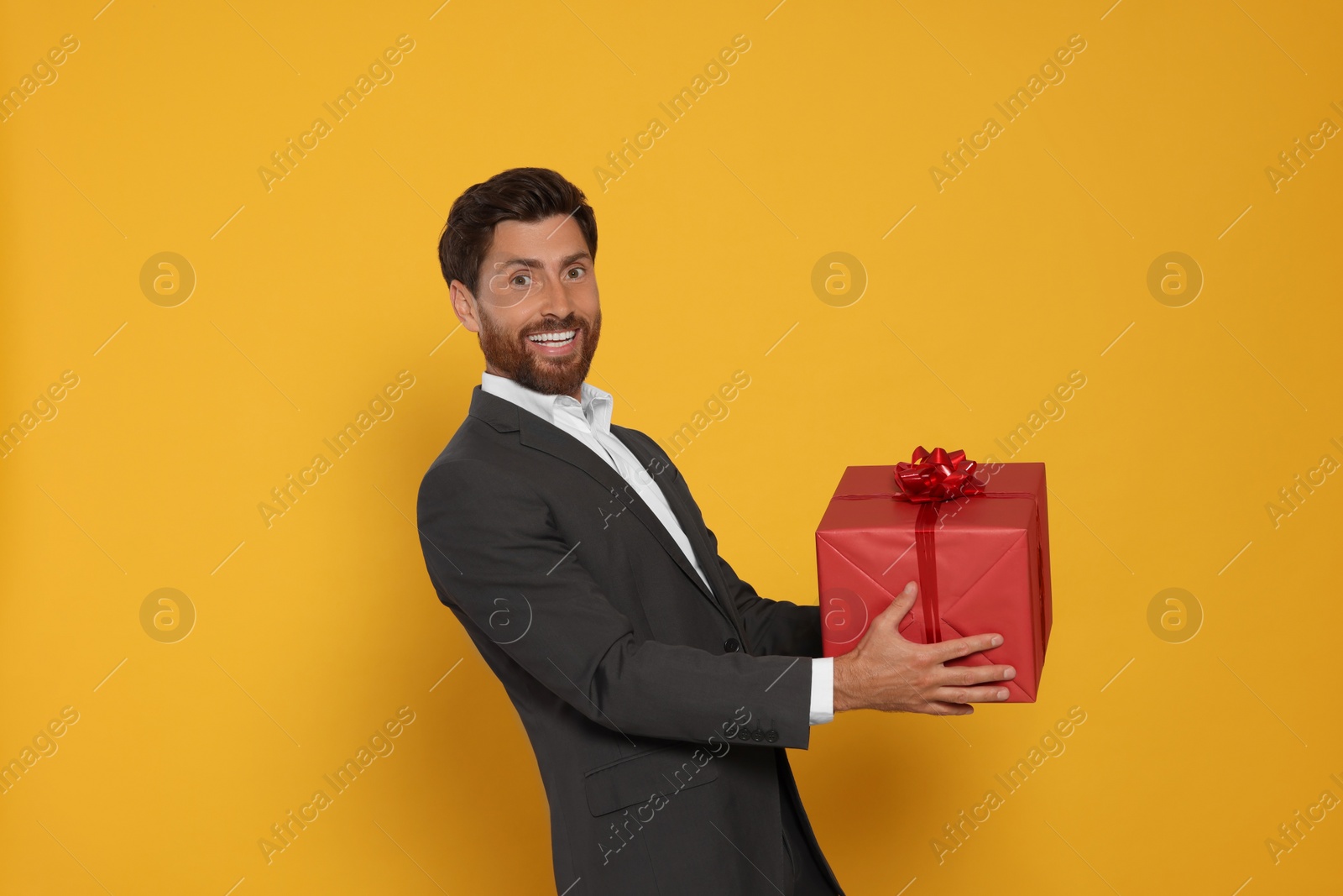 Photo of Handsome man holding gift box on yellow background