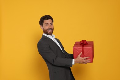 Photo of Handsome man holding gift box on yellow background