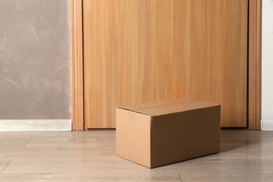 Photo of Cardboard box on floor near apartment entrance. Mockup for design