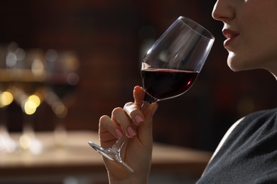 Photo of Woman with glass of red wine against blurred background, closeup. Space for text