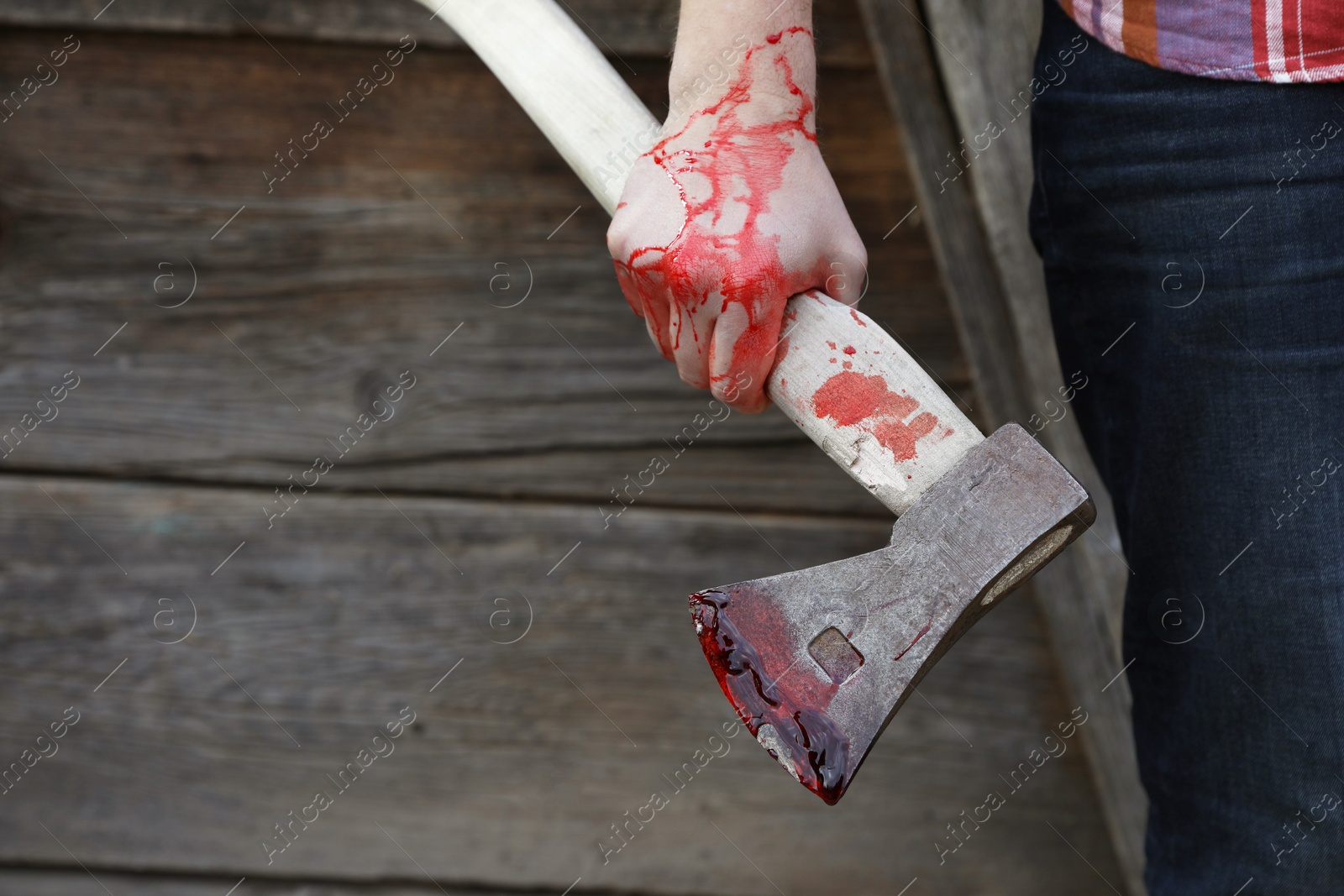 Photo of Man holding bloody axe outdoors, closeup. Space for text