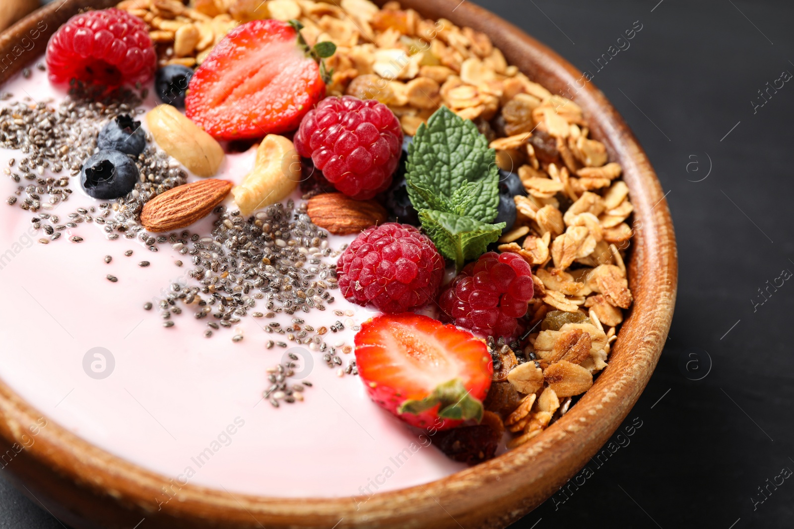 Photo of Tasty homemade granola with yogurt on dark grey table, closeup. Healthy breakfast