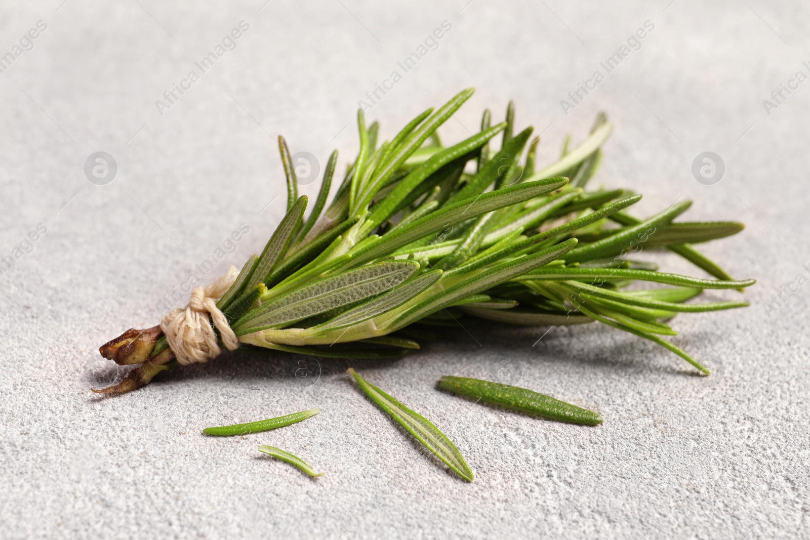 Photo of Bunch of fresh rosemary on light textured table, closeup