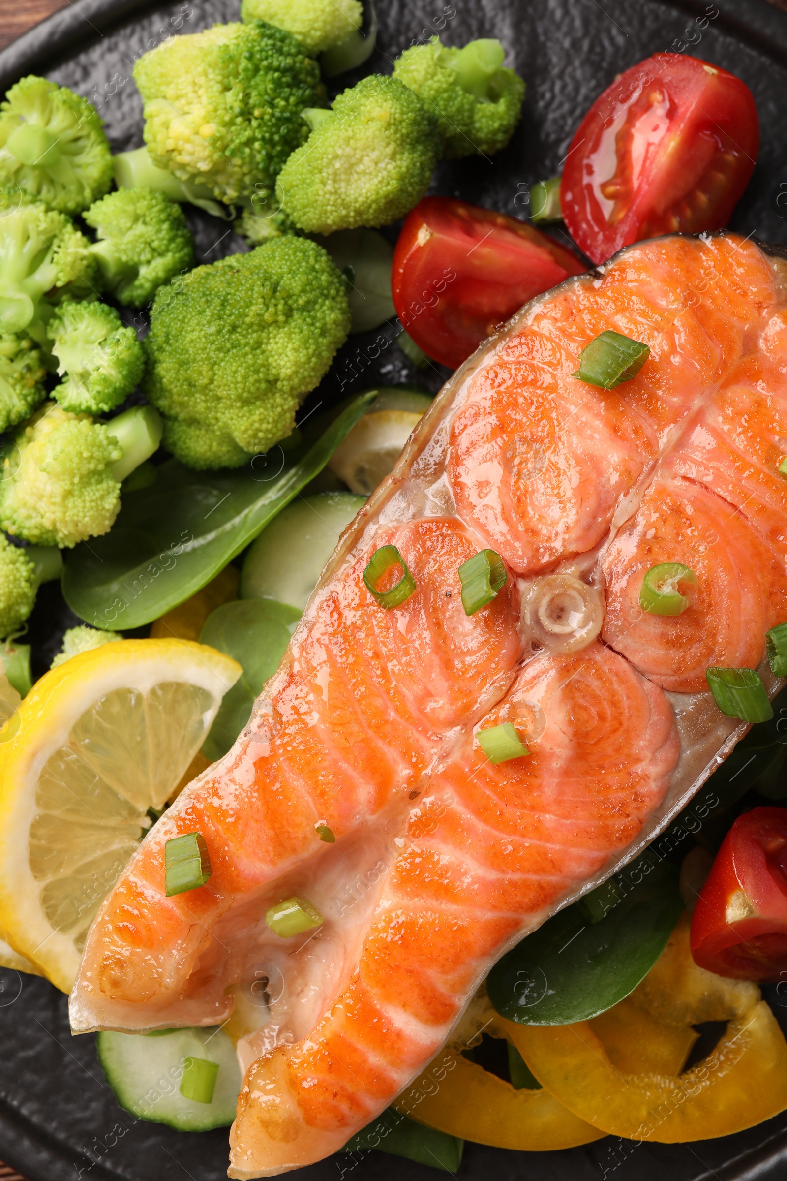 Photo of Healthy meal. Grilled salmon steak, green onion, lemon and vegetables on table, top view