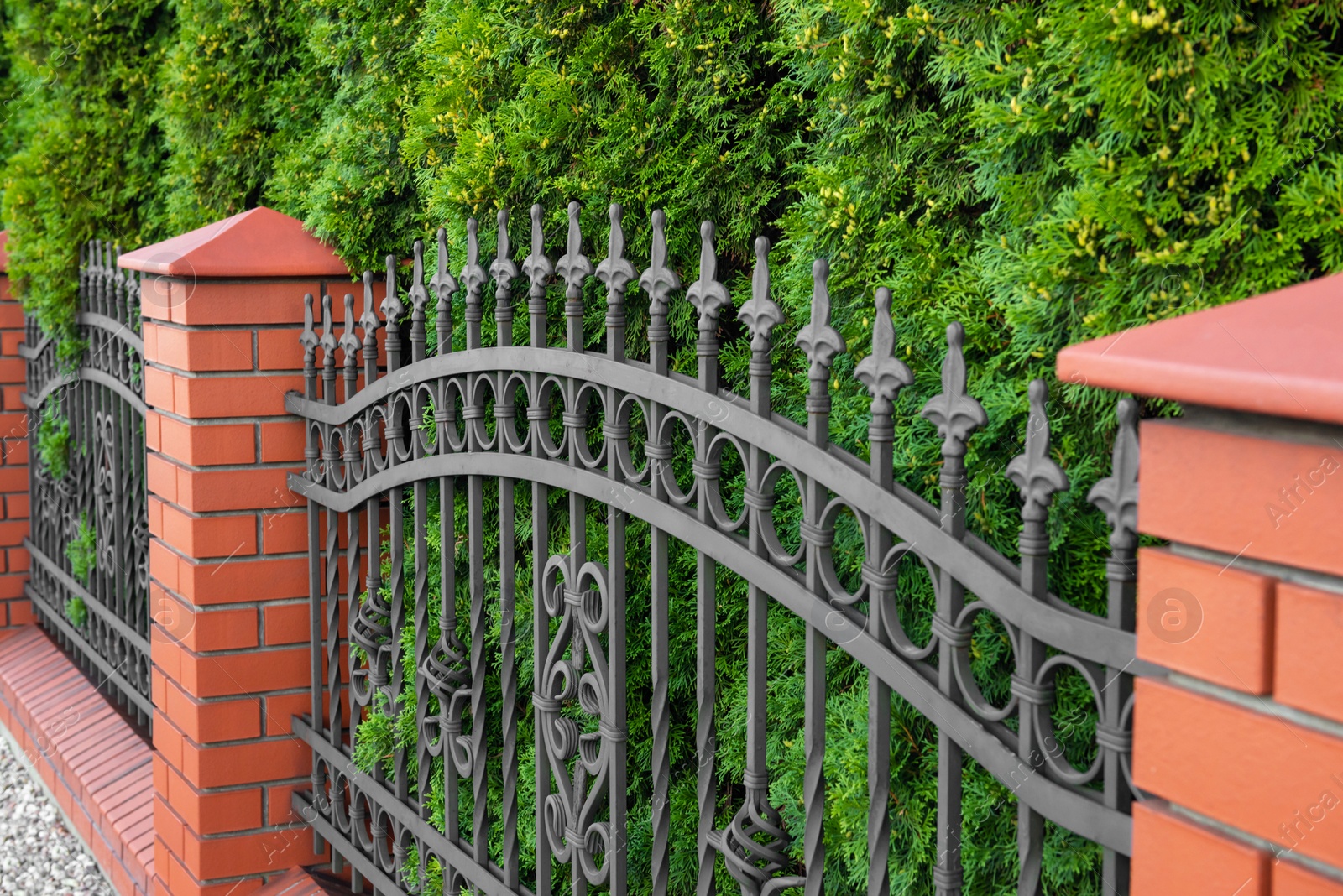 Photo of Beautiful brick fence with iron railing outdoors