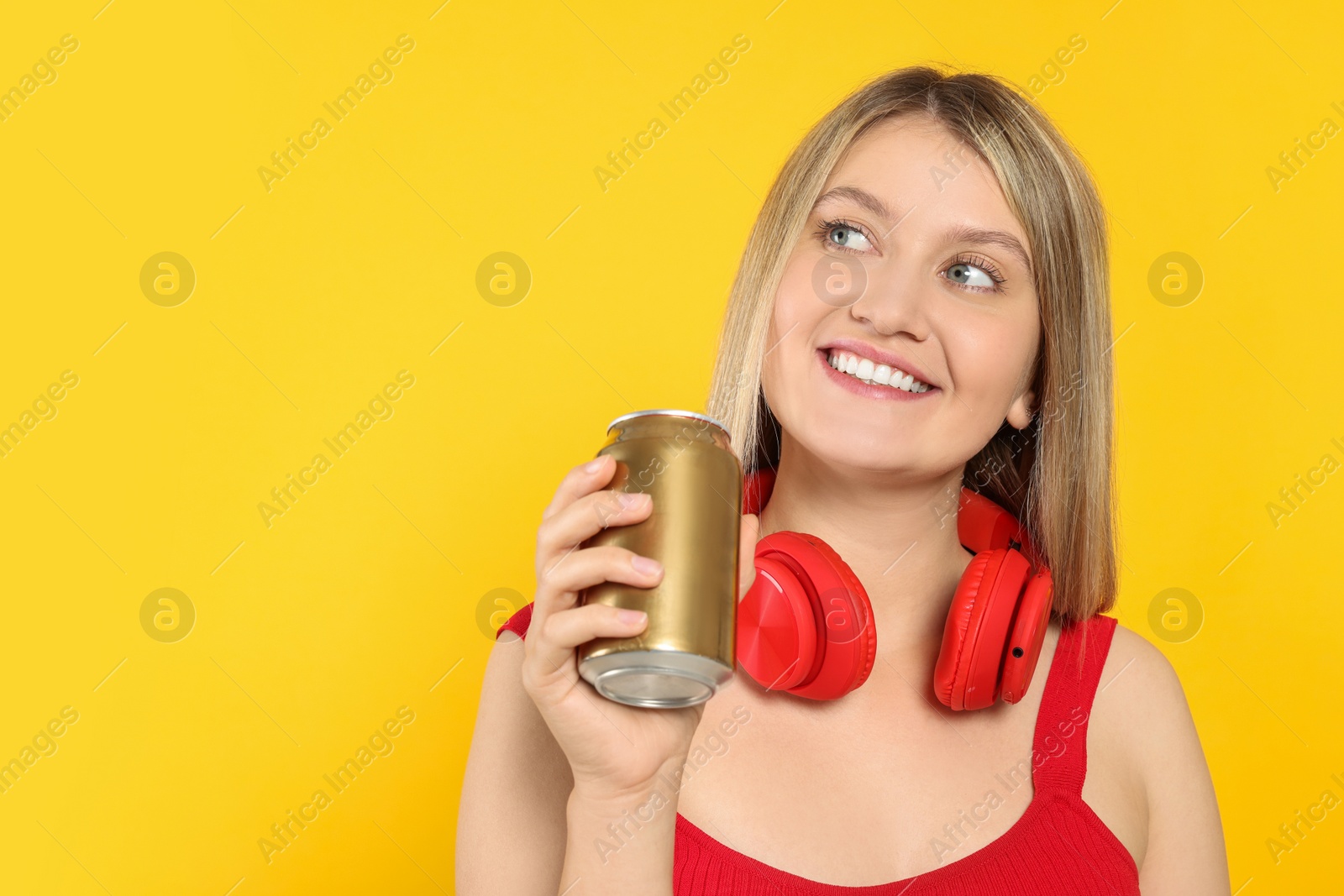 Photo of Beautiful happy woman holding beverage can on yellow background. Space for text