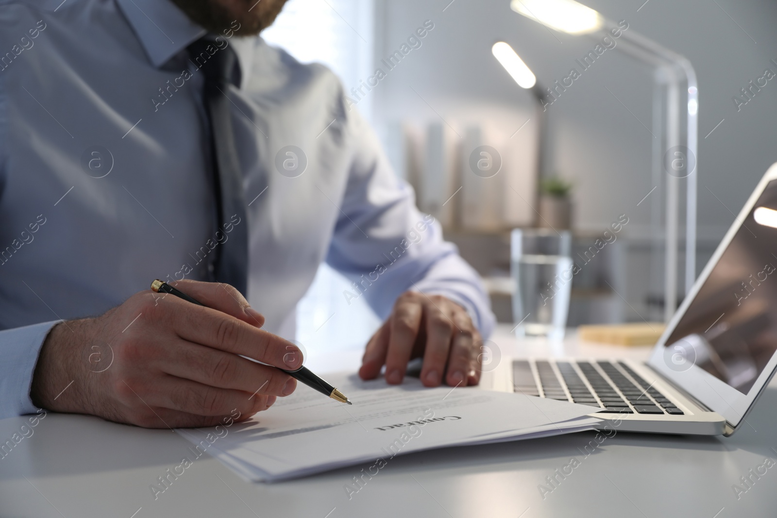 Photo of Businessman working with documents at white desk in office, closeup