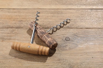 Two different corkscrews on wooden table, space for text