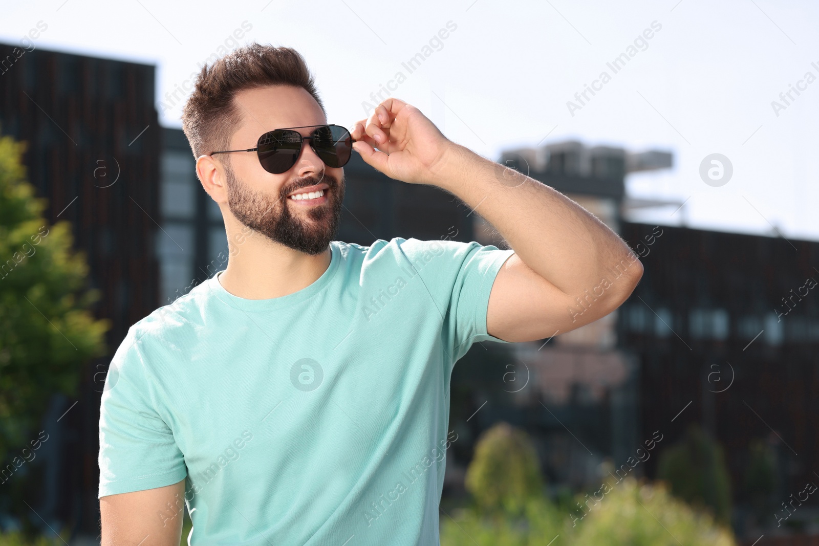 Photo of Handsome smiling man in sunglasses outdoors, space for text