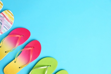 Photo of Different flip flops and space for text on blue background, flat lay. Summer beach accessories