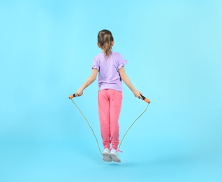 Photo of Active girl jumping rope on color background