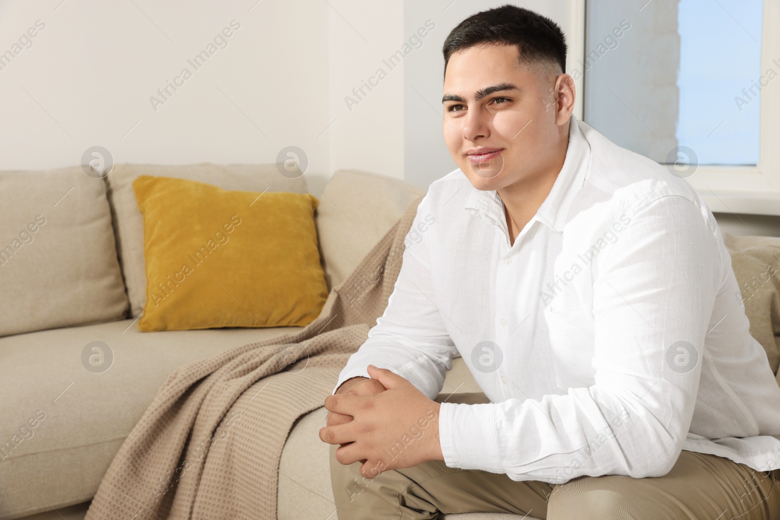 Photo of Happy young groom on sofa indoors. Wedding preparation