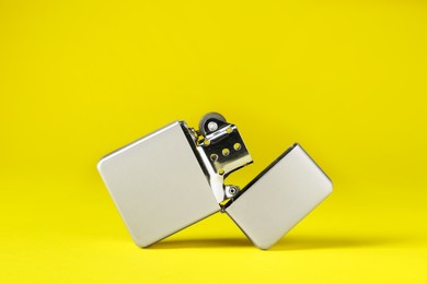 Photo of Gray metallic cigarette lighter on yellow background, closeup