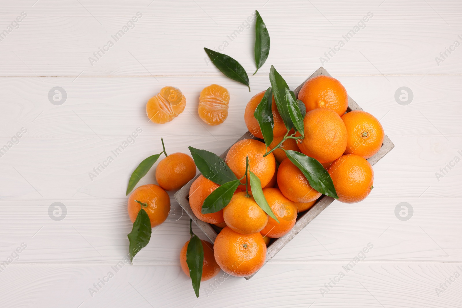 Photo of Delicious tangerines with leaves on white wooden table, flat lay