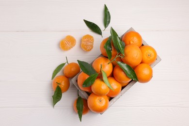 Photo of Delicious tangerines with leaves on white wooden table, flat lay