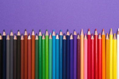 Photo of Colorful pencils on purple background, flat lay