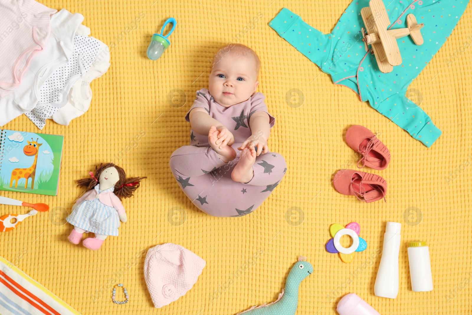 Photo of Cute little baby with clothing and accessories on color blanket, top view