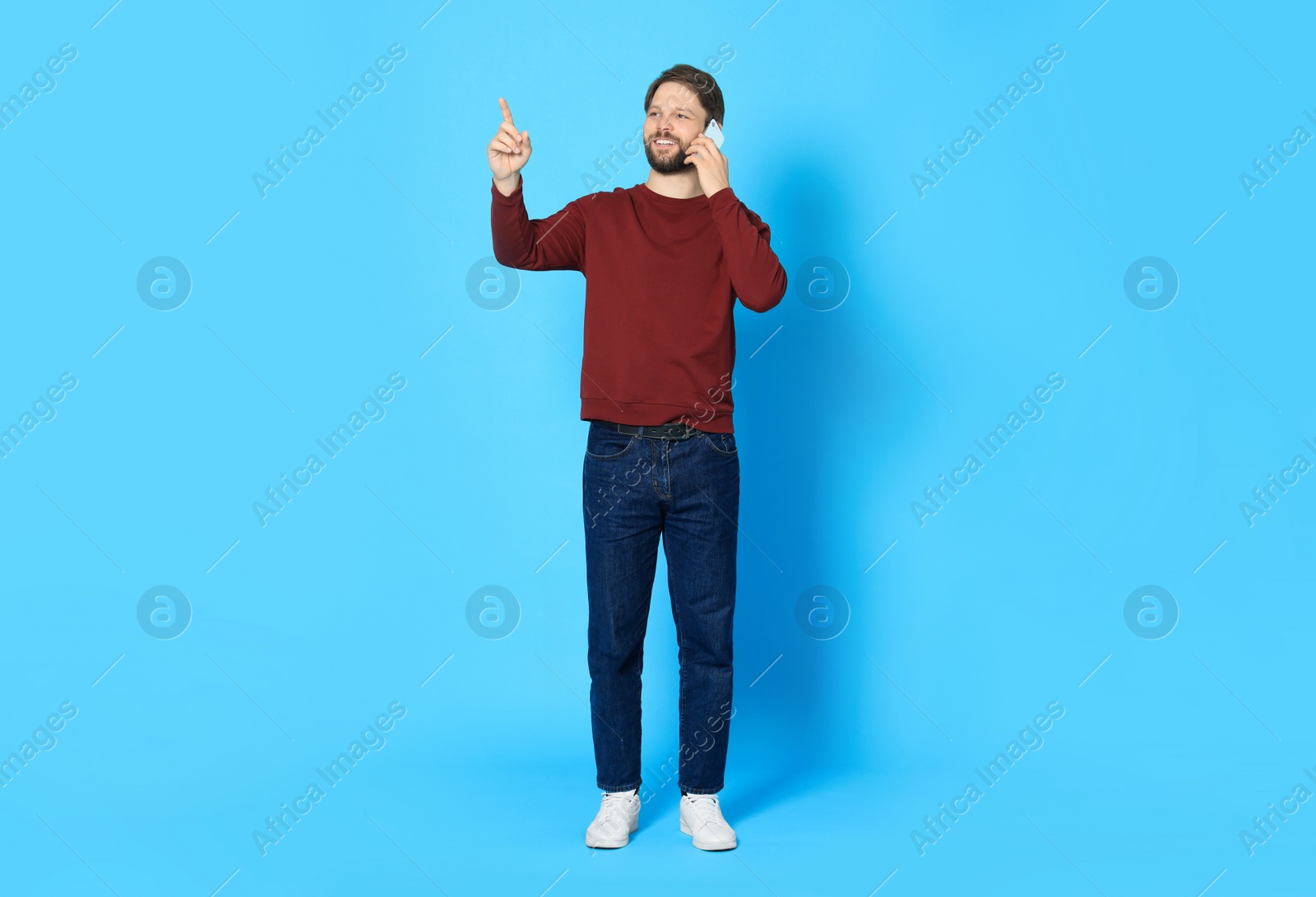 Photo of Man talking on smartphone against light blue background