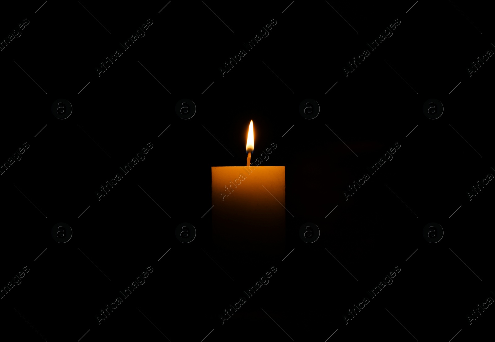 Photo of One burning wax candle on black background