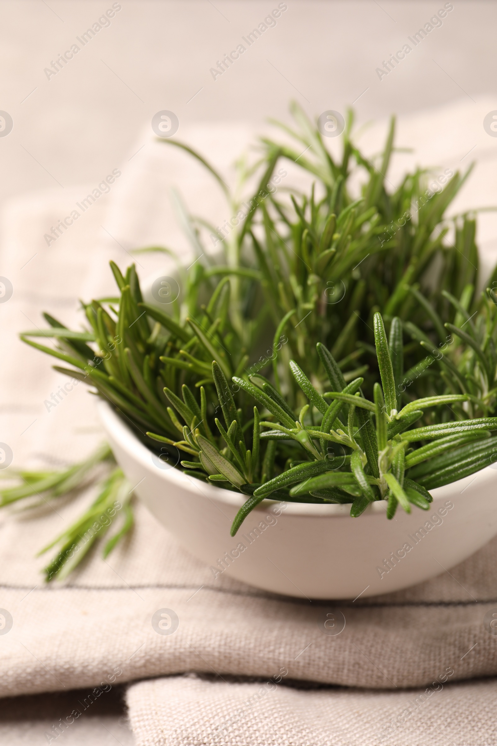 Photo of Bowl with fresh green rosemary on table, closeup