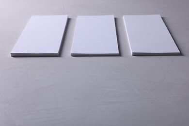 Photo of Blank business cards on light grey textured table, closeup. Mockup for design