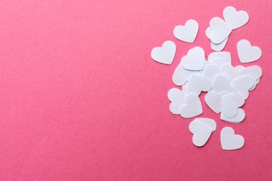 White paper hearts on pink background, flat lay. Space for text